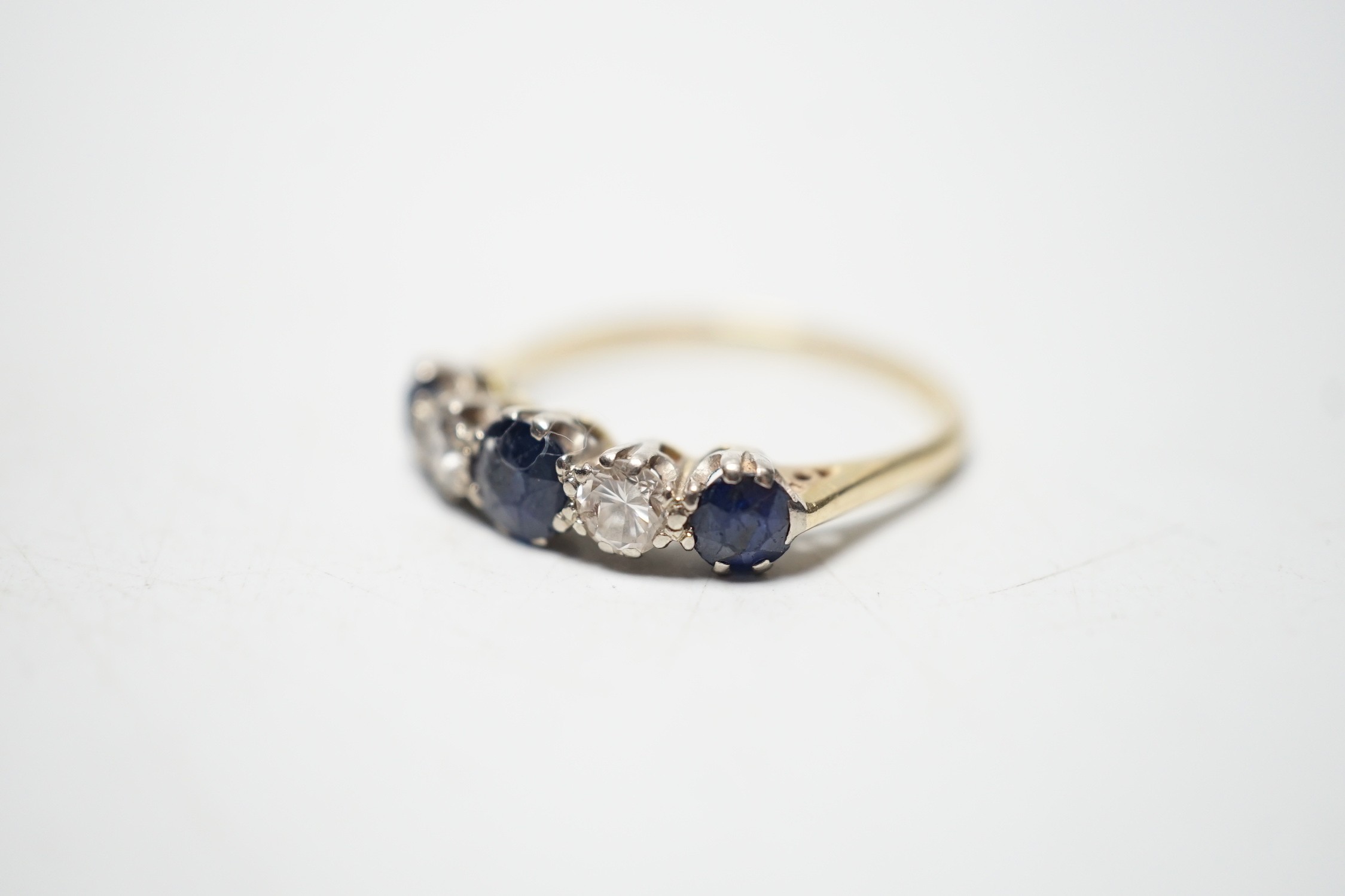 A modern 18ct gold, three stone sapphire and two stone diamond set half hoop ring, size R, gross weight 3.1 grams.